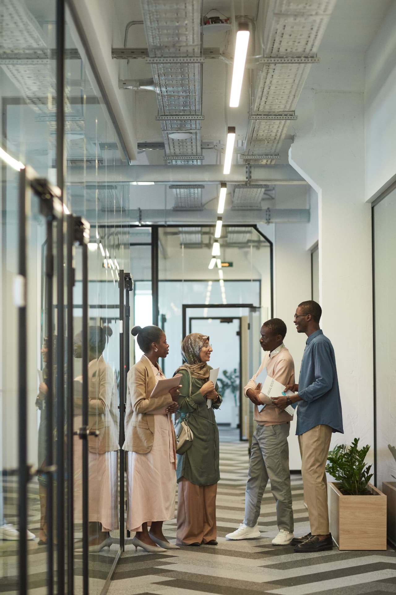 Four professionals talking together in a modern office corridor